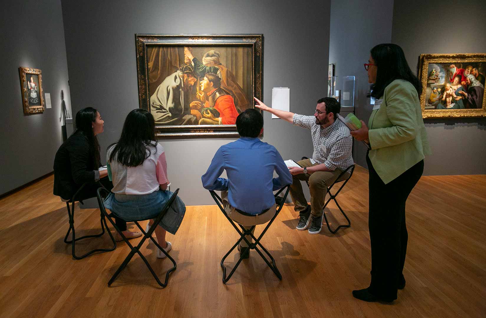 A group of students discuss the people depicted in a work of art with dermatologist Lynn McKinley-Grant.